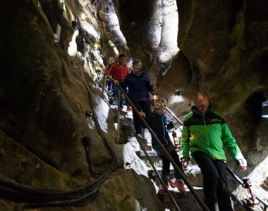 Eine Gruppe von Menschen wandert auf einer Treppe durch eine beeindruckende Höhlenlandschaft in Deutschland.