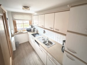 In der Küche gibt es einen Kühlschrank, eine Spüle und mehrere Küchengeräte sowie Arbeitsflächen zur Zubereitung von Speisen.