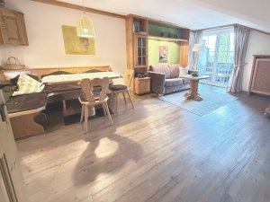 Der Raum zeigt eine offene Küche, einen Essbereich und einen Wohnbereich mit Zugang zur Terrasse. Tageslicht strömt herein.