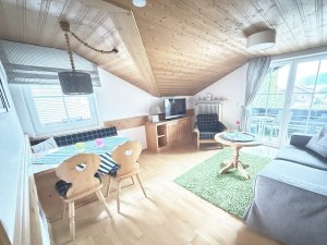 Diese Wohnung hat einen hellen Wohnbereich mit einem Tisch, Stühlen und Zugang zum Balkon. Der Raum ist gut ausgestattet.