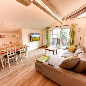 Wohnzimmer mit Essbereich und Balkon Das Bild zeigt ein Wohnzimmer mit einem Essbereich. Der Raum hat große Fenster und einen Balkon.