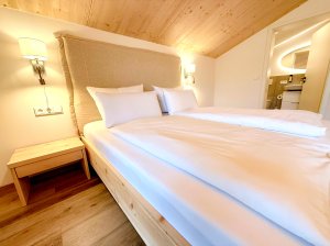 Ein Zimmer mit einem Doppelbett und hellen Wänden In einem modernen Raum steht ein großes Bett. Der Raum hat Holzdetails und eine warme Atmosphäre.