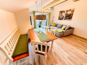 Wohngestaltung in einem modernen Raum Im Raum sind Tische und eine Couch zu sehen. Das Licht fällt durch große Fenster. Es ist ein heller Tag.