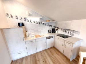Küche mit Bergmotiv und hellem Holzfußboden In dieser Küche ist eine Wand mit Bergsicht zu sehen. Die Arbeitfläche hat Kochgeräte und Zubehör.