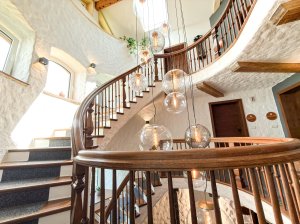 Treppenhaus mit Glasleuchten und Holzgeländer Das Treppenhaus zeigt ein gewundenes Geländer aus Holz und hängende Glasleuchten. Es ist hell und elegant gestaltet.
