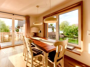 Helles Zimmer mit Tisch und Stühlen Im Raum stehen ein Tisch und Stühle. Durch das Fenster sieht man Bäume und ein Haus. Es ist hell und freundlich.