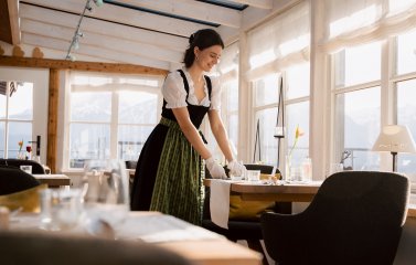 Eine Mitarbeiterin im Biohotel Eggensberger in Füssen, Hopfen am See deckt den Tisch im Restaurant.