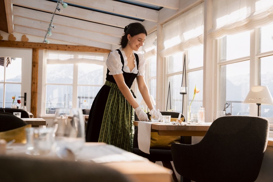 Eine Mitarbeiterin im Biohotel Eggensberger in Füssen, Hopfen am See deckt den Tisch im Restaurant.