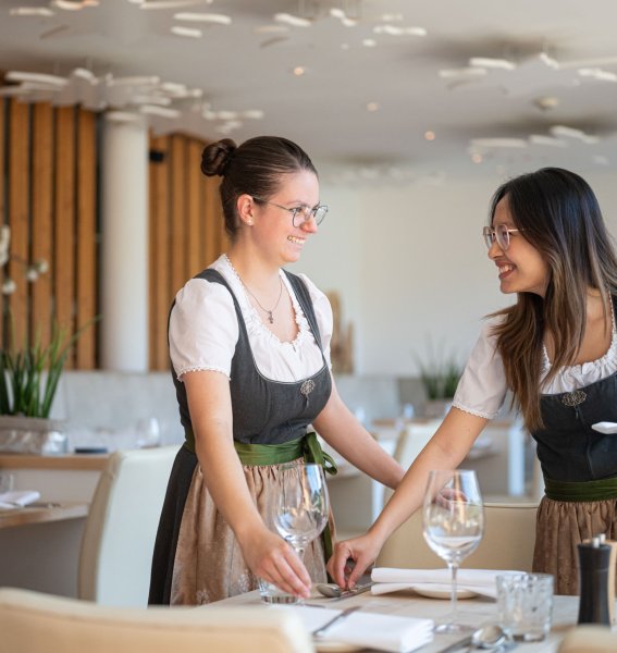 Azubis decken gemeinsam einen Tisch ein und lachen
