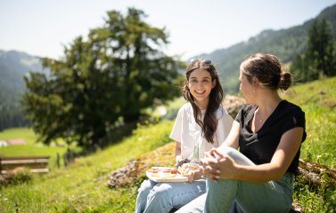 Zwei Azubis sitzen im Freien zusammen und genießen in ihrer Freizeit Getränke und Snacks