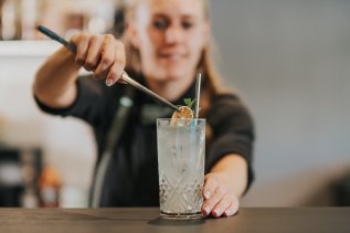 Eine Mitarbeiterin vom PANORAMA Allgäu-Spa-Resort in Rückholz finalisiert einen Cocktail