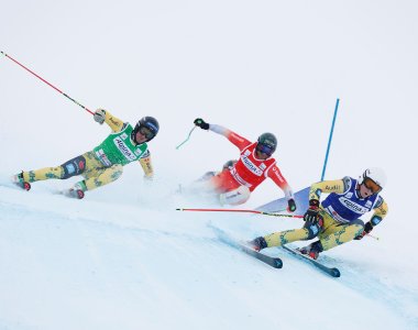 Schnelle Abfahrten beim Skirennen in den Alpen Drei Skifahrer rasen bei einem Wettkampf in den Alpen auf einer verschneiten Piste.