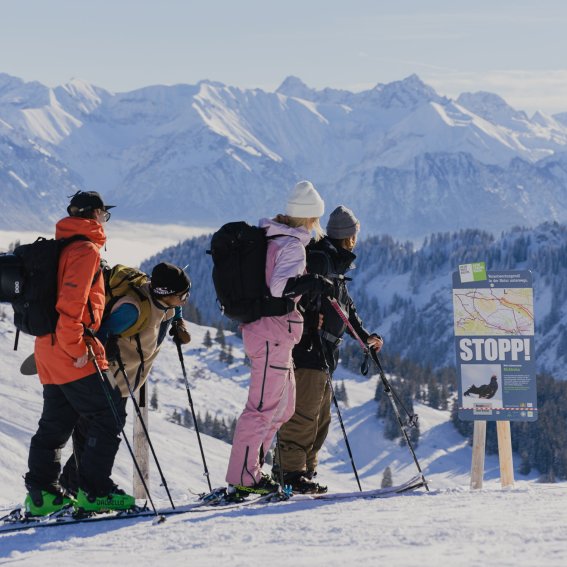 Gruppe von vier Personen genießt die Berglandschaft und plant den weiteren Weg während eines Tages im Schnee.