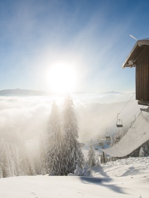 Bei klarem Wetter glänzt der Schnee unter der Morgensonne. Eine Skiliftstation steht einsam in der winterlichen Landschaft.