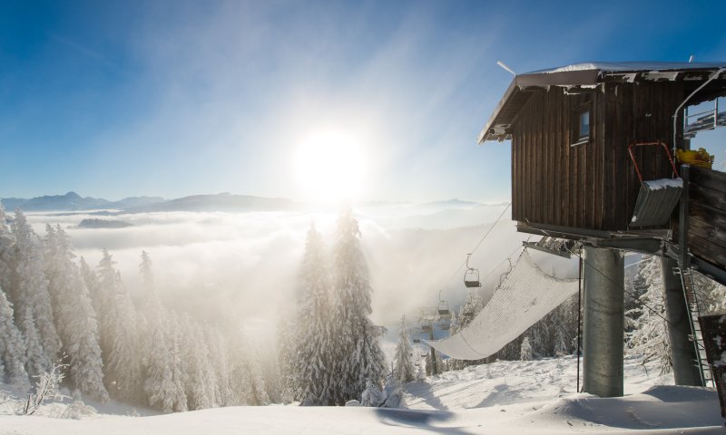 Bei klarem Wetter glänzt der Schnee unter der Morgensonne. Eine Skiliftstation steht einsam in der winterlichen Landschaft.