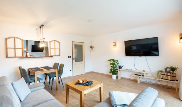 Helles Wohnzimmer mit gemütlicher Sitzecke und Esstisch, ideal für gesellige Abende oder Entspannung zu Hause.