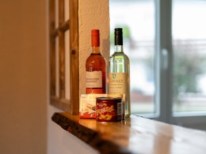 Auf der Durchreiche von der Küche stehen Wein und Snacks, die eine gemütliche Atmosphäre im Raum schaffen.