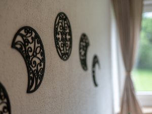 Filigrane schwarze Holzverzierungen formen Halbmonde an der Wand eines gemütlichen Schlafzimmers mit Fensterblick ins Grüne.
