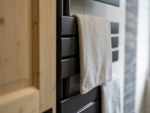 In einem modernen Badezimmer hängen frische Handtücher an einem eleganten Heizkörper aus Metall und Holz.