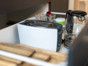 In der Küchenschublade sind ein Toaster und Küchenutensilien sichtbar. Die Schublade enthält auch Gläser und einen Mixer.