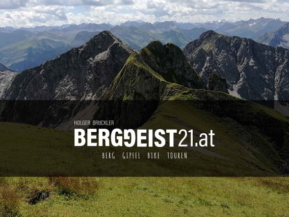 Atemberaubende Berglandschaft mit grünen Wiesen und majestätischen Gipfeln unter einem wolkigen Himmel in den Alpen.