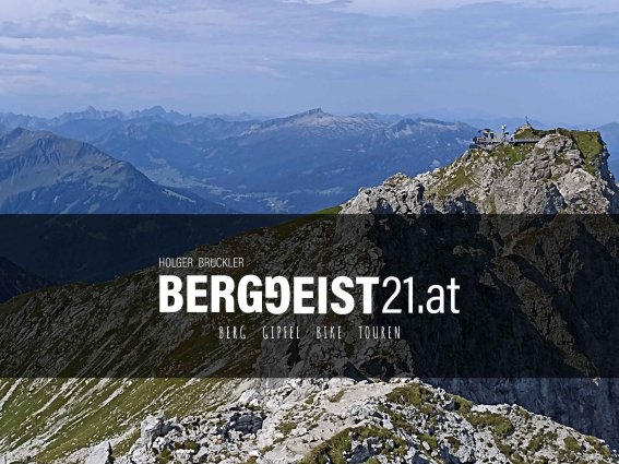 Wanderer genießen die beeindruckende Aussicht auf die Alpen und die umliegenden Gipfel an einem klaren, sonnigen Tag.