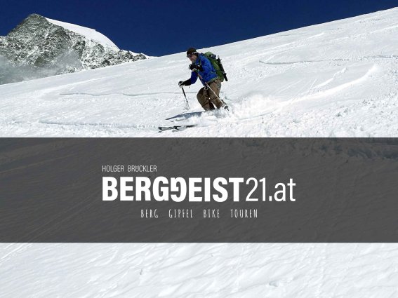 Ein Skifahrer genießt die Abfahrt im frischen Pulverschnee während eines klaren, sonnigen Tages in den Bergen.