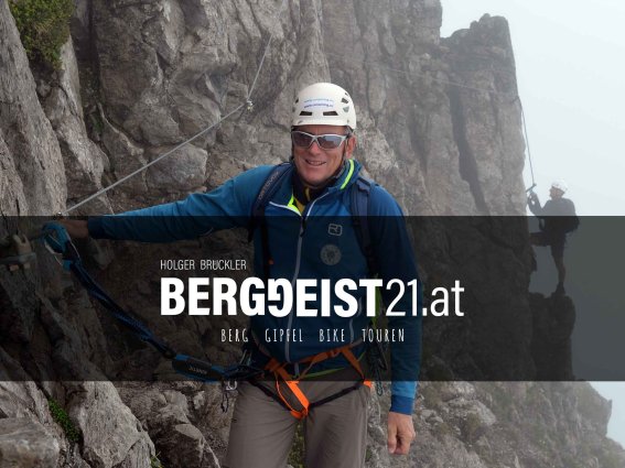 Ein Bergsteiger sichert sich während eines herausfordernden Aufstiegs in den Alpen an einem schroffen Felsen.