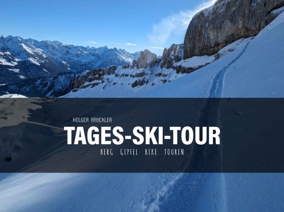 Eine Gruppe von Skifahrern genießt eine Tagesski-Tour in den Bergen unter strahlendem Himmel und glitzerndem Schnee.