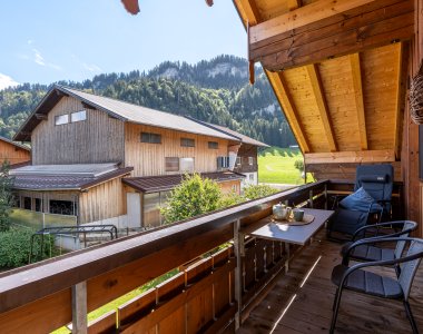 Holzbalkon mit Sitzgelegenheit und weitem Blick über Obermaiselstein-Ried in die Allgäuer Berge – Bergheimat Ferienwohnungen in Obermaiselstein-Ried im Allgäu.