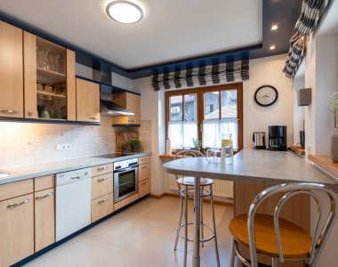 Moderne Einbauküche mit Backofen, Geschirrspüler, Kaffeemaschine und Frühstückstheke mit Barhockern – Bergheimat Ferienwohnungen in Obermaiselstein-Ried im Allgäu.