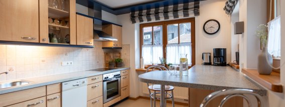 Moderne Einbauküche mit Backofen, Geschirrspüler, Kaffeemaschine und Frühstückstheke mit Barhockern – Bergheimat Ferienwohnungen in Obermaiselstein-Ried im Allgäu.