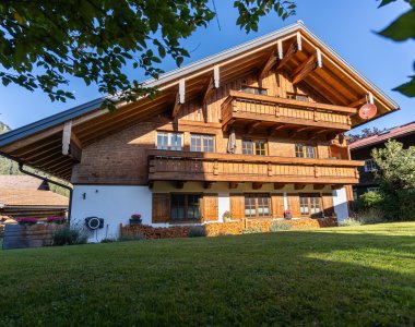 Klassisches Allgäuer Holzhaus mit umlaufenden Holzbalkonen und großem Garten in Obermaiselstein-Ried – Teil der Bergheimat Ferienwohnungen im Oberallgäu.