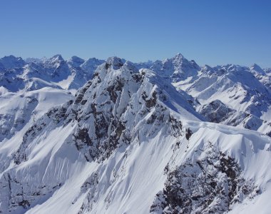 Tief verschneite Gipfel und Grate der Allgäuer Alpen unter strahlend blauem Himmel – Bergheimat Ferienwohnungen in Obermaiselstein-Ried im Allgäu.