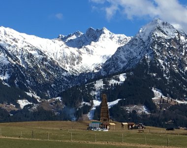 Frühlingswiese im Tal vor den noch schneebedeckten Gipfeln der Allgäuer Alpen – Bergheimat Ferienwohnungen in Obermaiselstein-Ried im Allgäu.