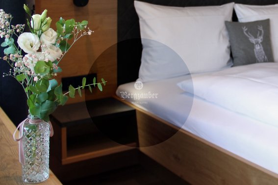 Ein elegantes Schlafzimmer mit einem gemütlichen Bett, dekoriert mit einem schönen Blumenstrauß in einer Vase.