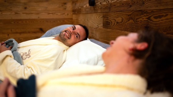 Entspannte Zeit, Wellness Zwei Personen liegen in Bademänteln auf Betten und genießen eine entspannte Zeit in einem Wellnessbereich.