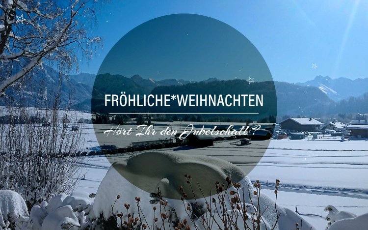 Eine verschneite Landschaft mit Bergen und Weihnachtswünschen in einem ruhigen Dorf während des Tages.