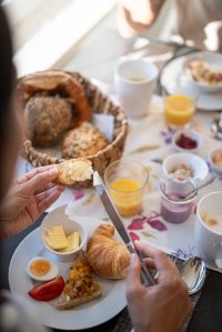 Am Tisch wird ein leckeres Frühstück mit Croissants, Eiern und Marmelade vorbereitet. Gemütliche Atmosphäre im Garten.