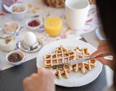 Reichhaltiges Frühstück mit Waffeln an einem schön gedeckten Tisch mit verschiedenen Beilagen.