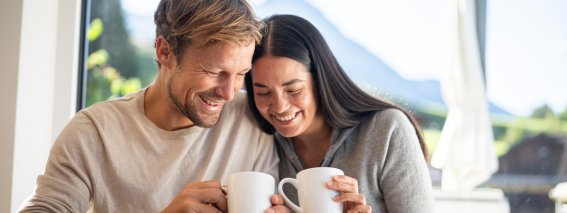 Ein Paar genießt gemeinsam ein Frühstück mit Kaffee und Blick auf die Berge. Glückliche Momente in der Natur.