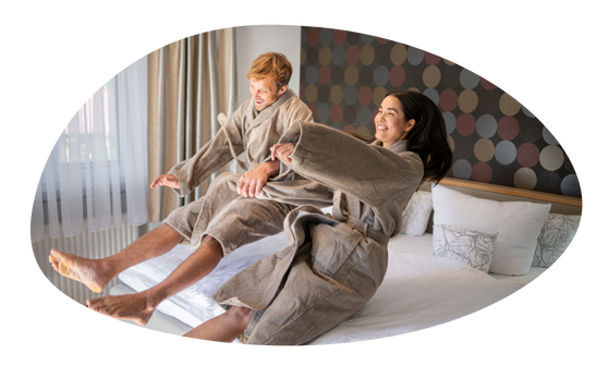 Par im Morgenmantel lässt sich mit Schwung auf das Bettfallen