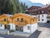 Zwei moderne Ferienhäuser stehen in einer schönen Berglandschaft in den Alpen. Urlauber genießen die Natur. Neue Ferienhäuser in den Alpen