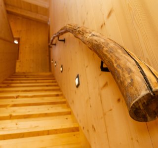 Treppe mit einem einzigartigen Holzhandlauf in einem hellen Raum aus Dielen.