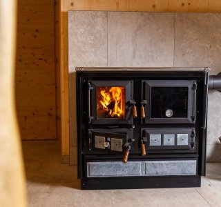 Eine elegante Holzheizung brennt in einem gemütlichen, modernen Raum mit Holzverkleidung und warmem Licht.