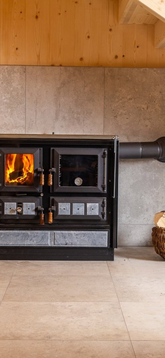 Ein Holzofen brennt in einem hellen Raum mit Holzregalen. Der Raum strahlt Gemütlichkeit und Wärme aus.