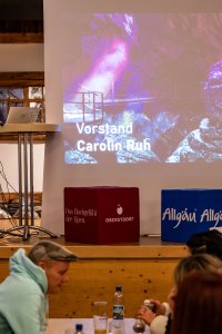 Ansprache während einer Versammlung. Die Veranstaltung findet in einem Raum mit vielen Teilnehmern statt.