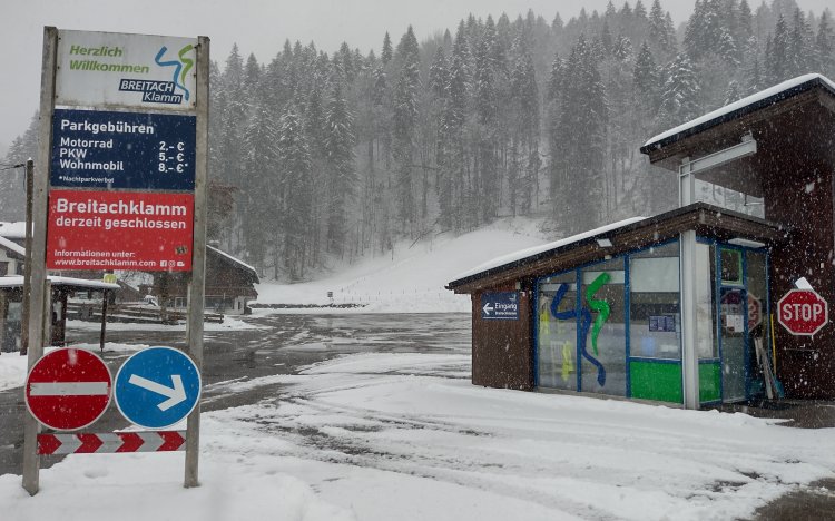 Ein Parkplatz an einer Sehenswürdigkeit bei Schnee. Ein Schild zeigt die Gebühren und den Geschlossen-Status der Breitachklamm.