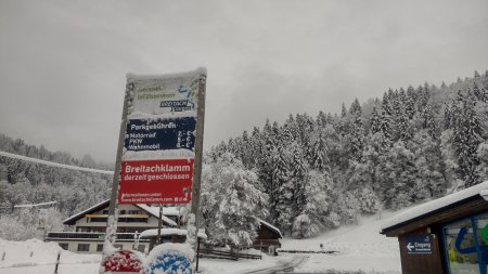 Ein Parkplatz an einer Sehenswürdigkeit bei Schnee. Ein Schild zeigt die Gebühren und den Geschlossen-Status der Breitachklamm.