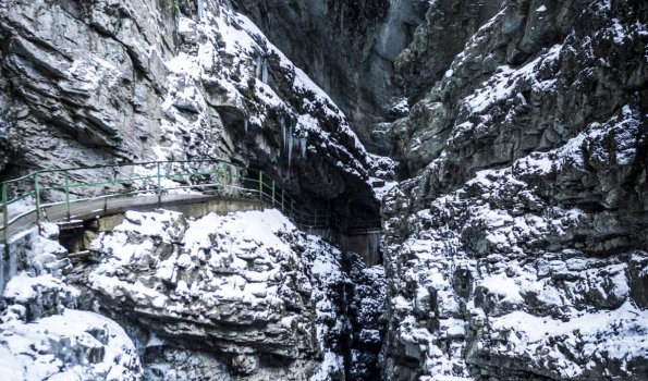 Ein Weg führt durch Schnee und Eis in die Klamm Hochformat